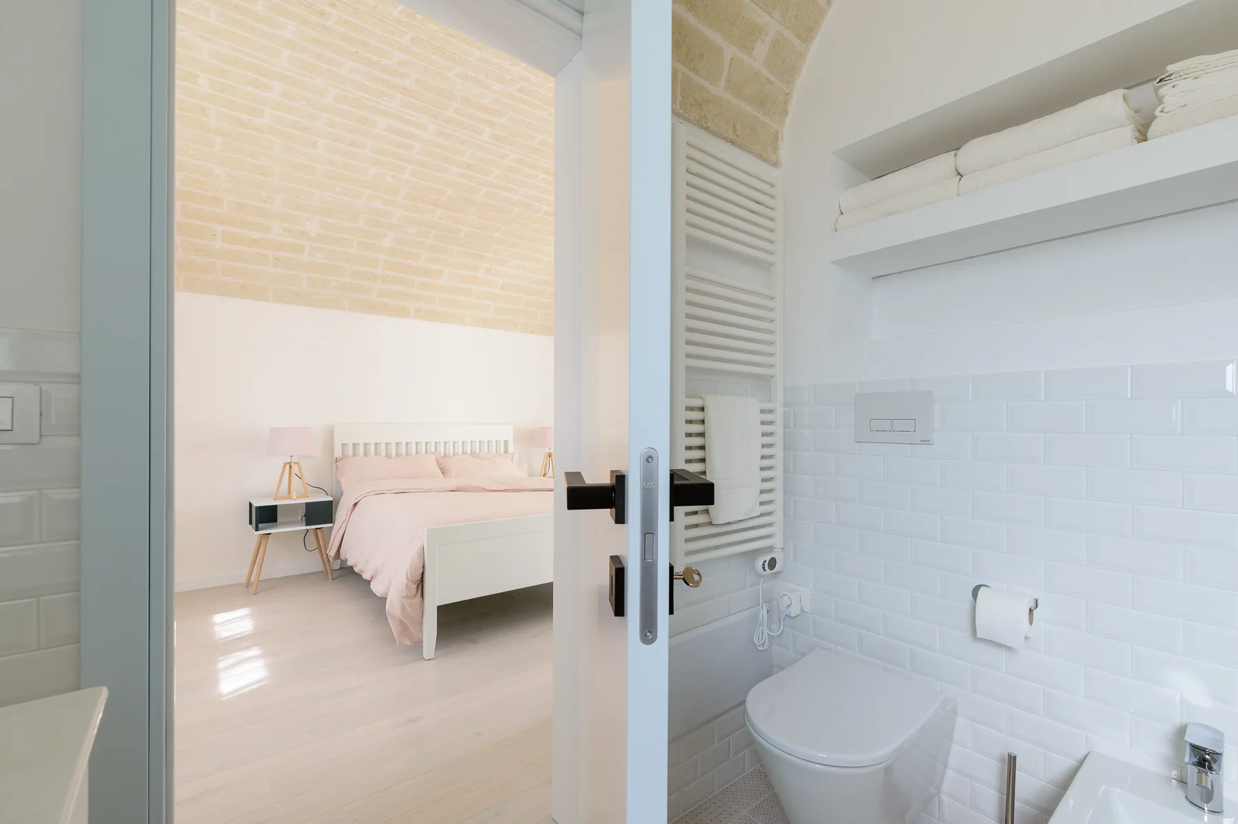 A bedroom is visible through an open doorway beside a bathroom with a toilet.