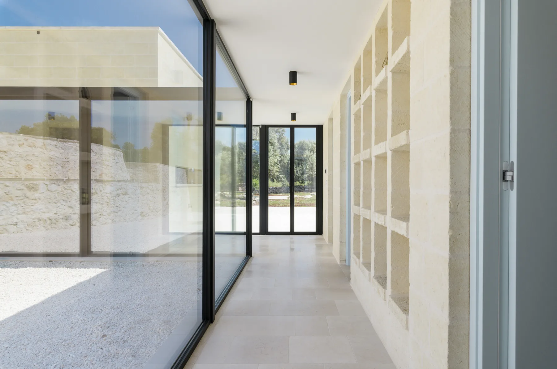 A bright interior hallway with glass walls and doors at the far end.