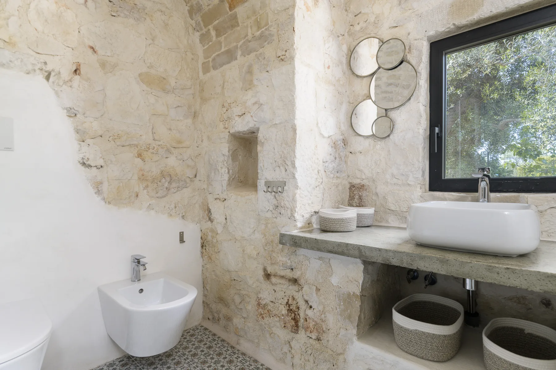 A stone bathroom with a white sink beneath a window.