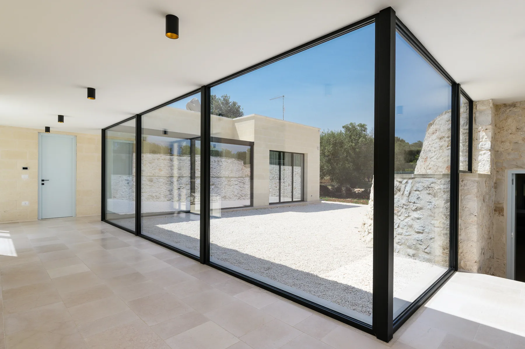 A bright glass-walled interior opens onto a sunlit courtyard.