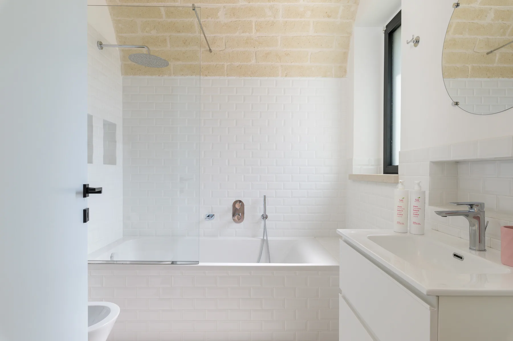A bright bathroom with a bathtub, shower fixture, and vanity.