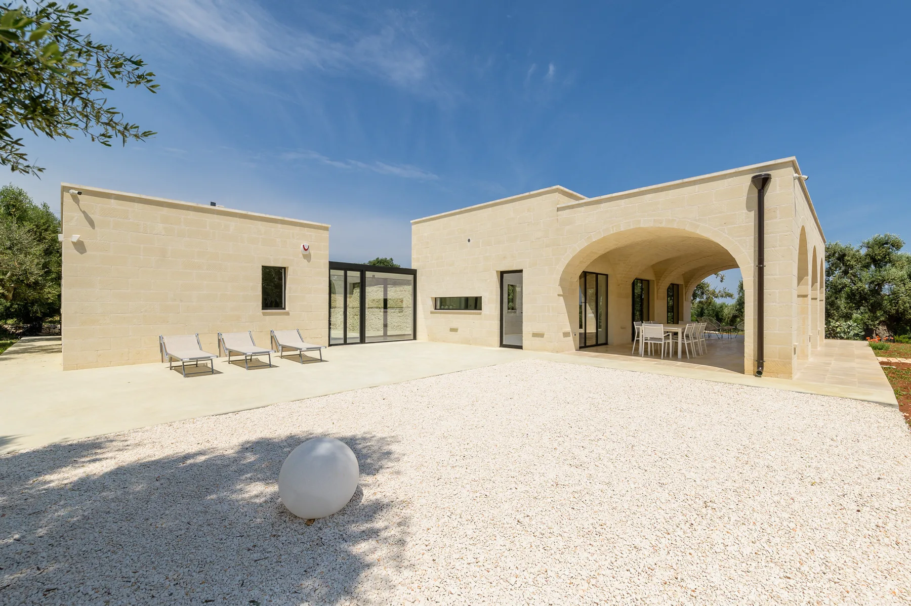 A modern building opens onto a bright courtyard with outdoor seating.
