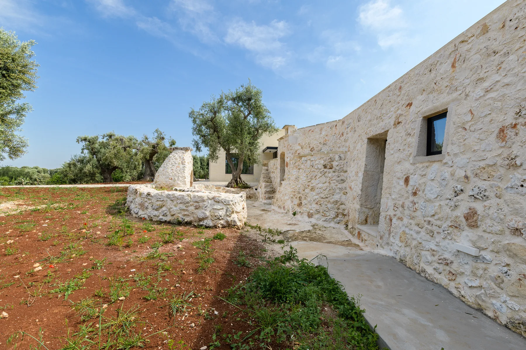 A stone building borders a small garden and paved walkway.