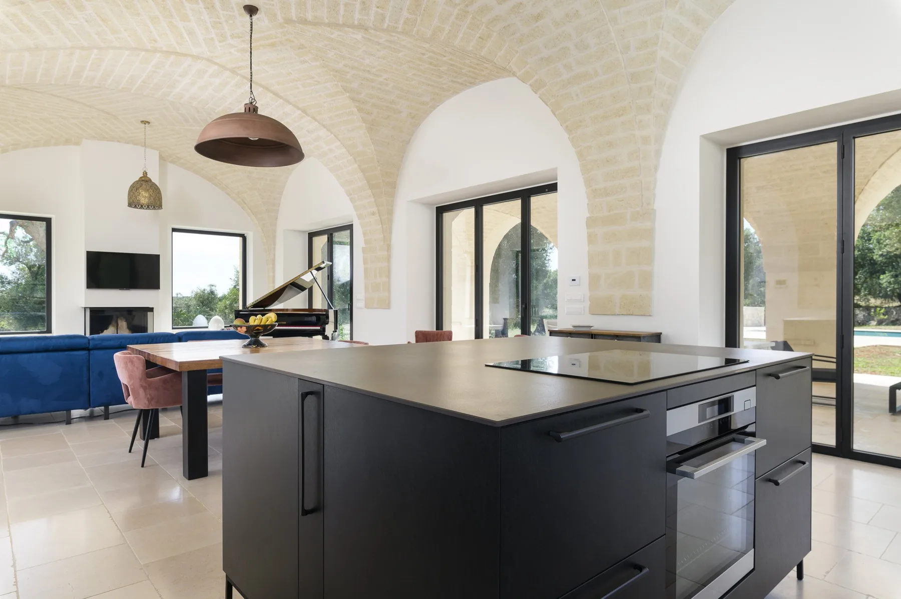 A bright kitchen and dining area features a large island beneath vaulted brick arches.