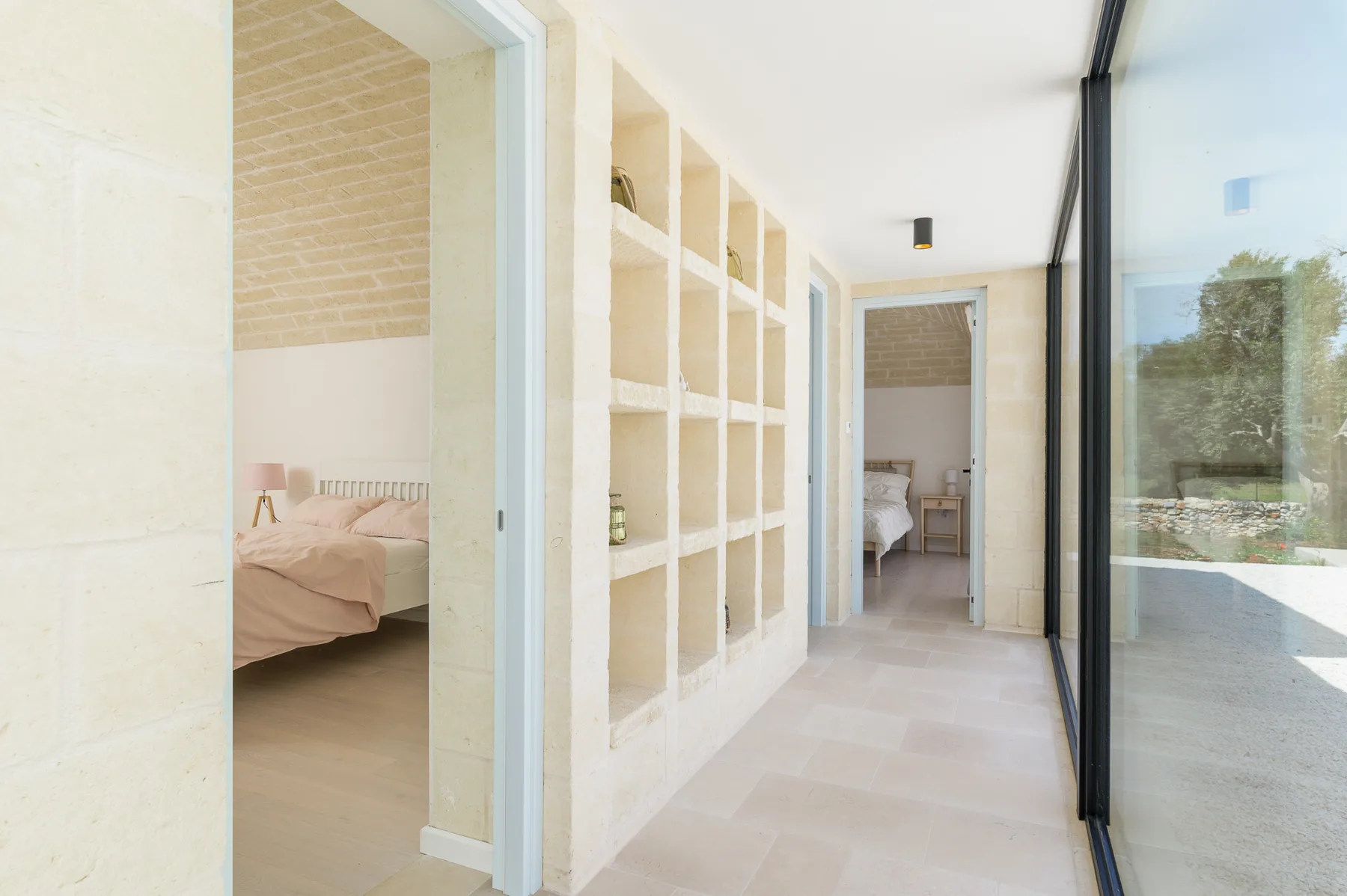 A bright hallway with built-in shelving and open doorways to bedrooms.