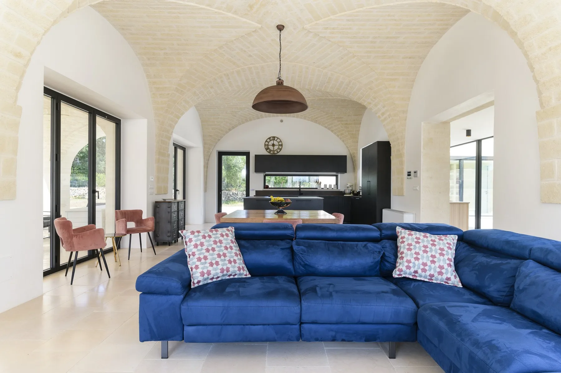 A bright living room features blue seating beneath a vaulted ceiling.