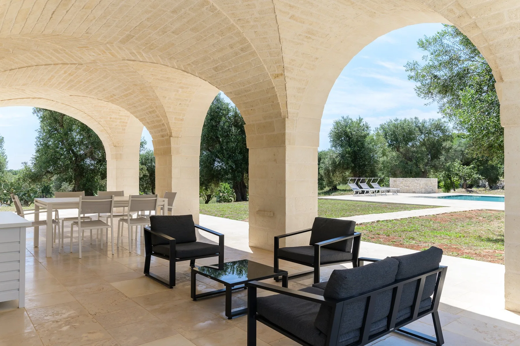 A covered outdoor seating area opens onto a garden and swimming pool.