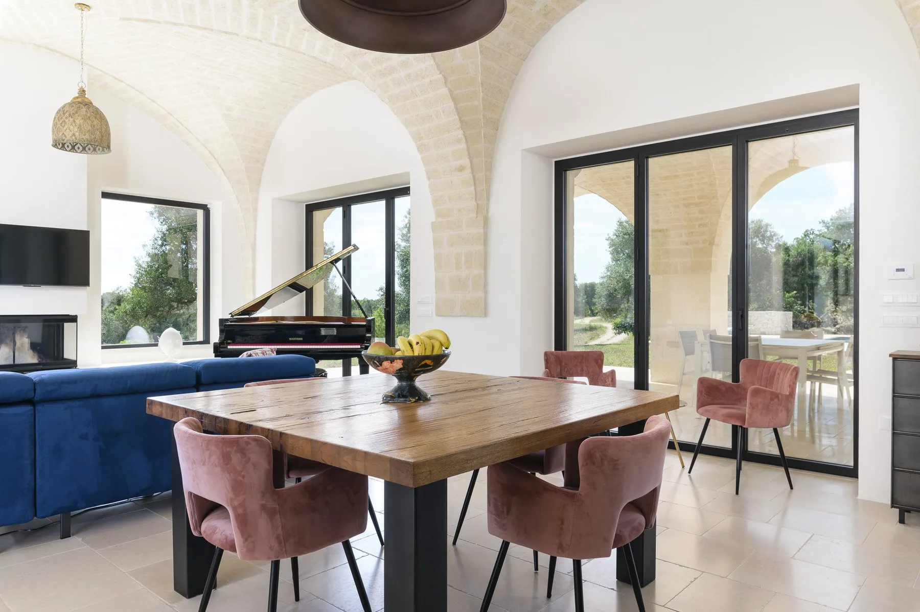 A dining area with a wooden table and seating beside large windows.