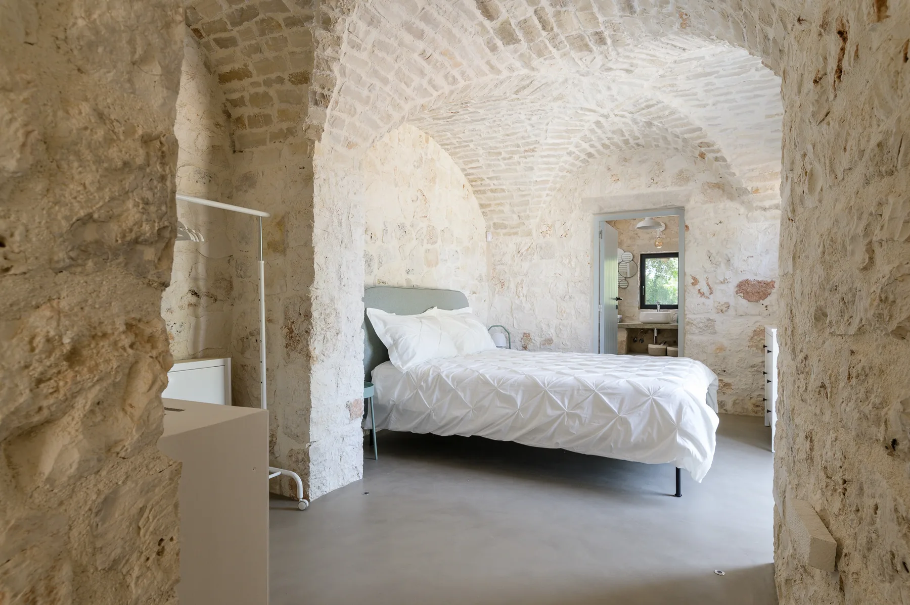 A bedroom with a bed beneath a vaulted stone ceiling.
