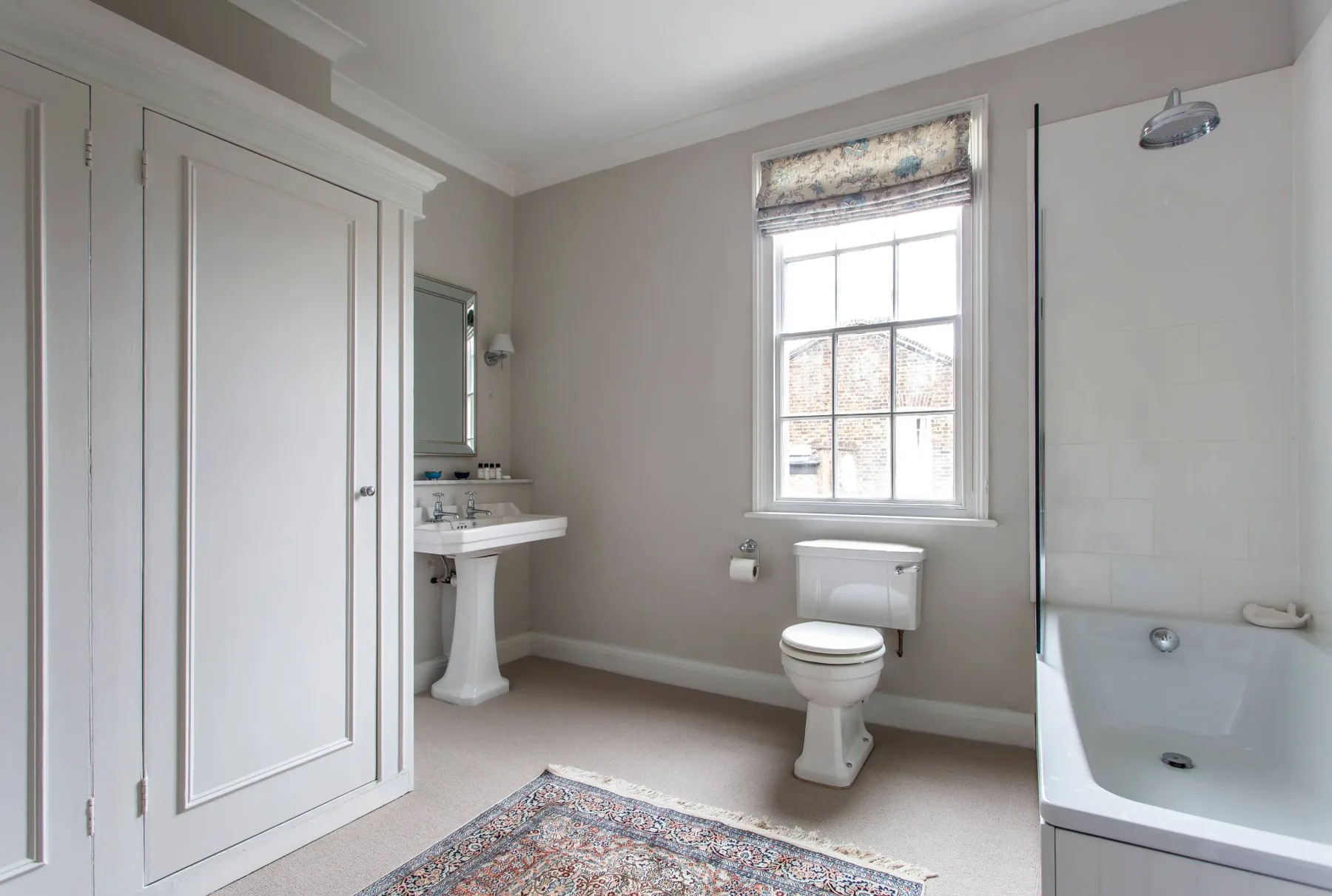 Un baño luminoso con bañera, inodoro y lavabo con pedestal.
