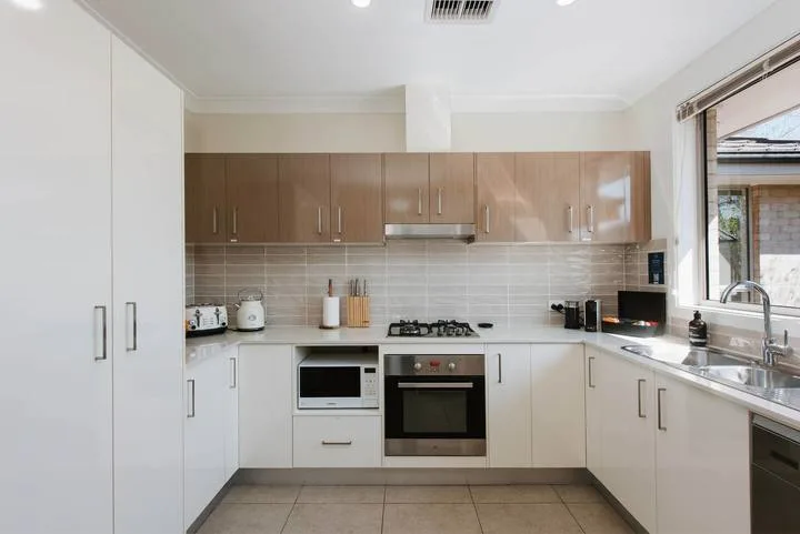 Una cocina moderna con gabinetes blancos, una estufa y un horno.