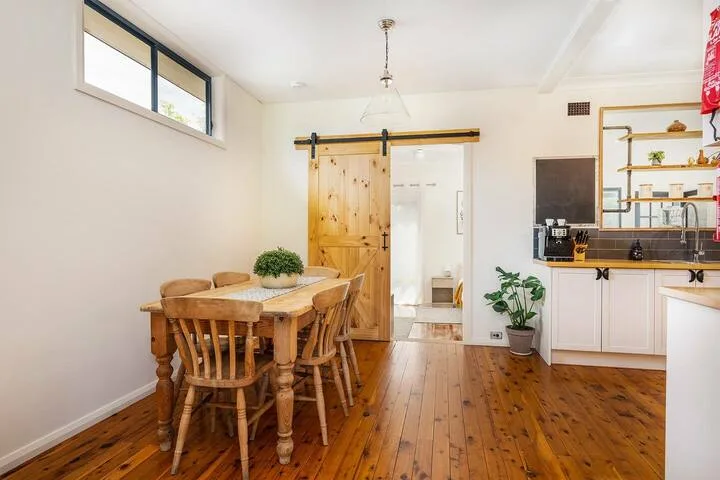 Un comedor con una mesa de madera junto a una cocina abierta.