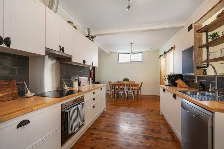 Una cocina con encimeras a ambos lados y una mesa de comedor al fondo.