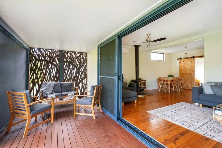 Un patio con asientos se abre a una sala y comedor con pisos de madera.