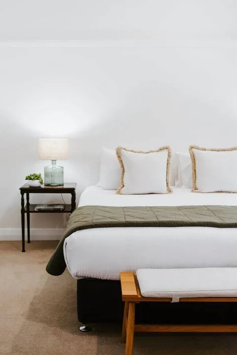 Un dormitorio con una cama tendida y una pequeña mesita de noche.