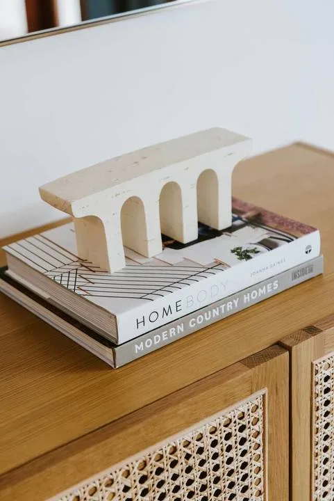 Un mueble de madera con puertas de entramado sostiene unos libros y un objeto escultórico.