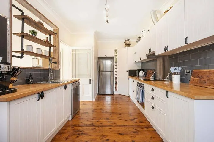 Una cocina alargada y luminosa con encimeras de madera y estantes abiertos.