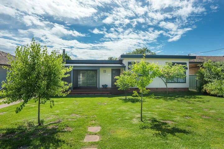 Una casa moderna de una planta da a un amplio césped con árboles jóvenes.