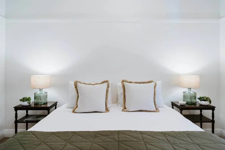 Un dormitorio con una cama bien tendida y mesitas de noche a juego.