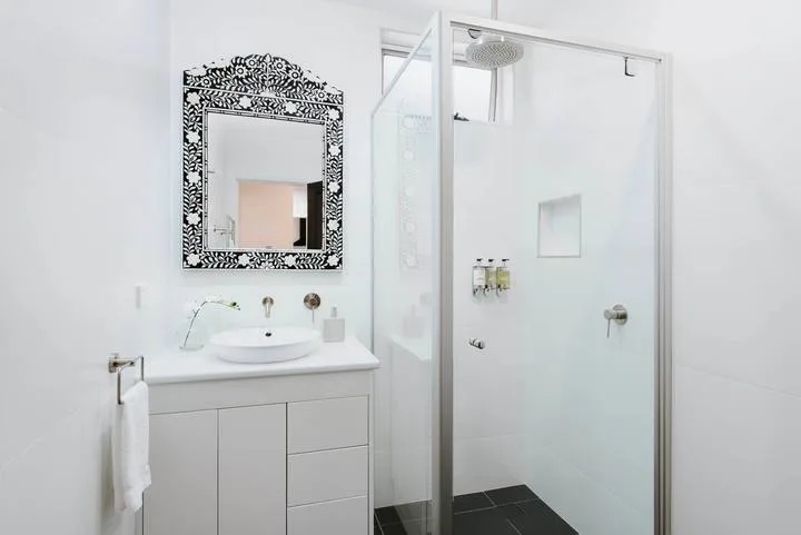 Un baño luminoso con lavabo y ducha de vidrio.