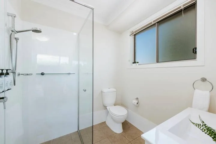 Un baño luminoso con ducha, inodoro y bañera.