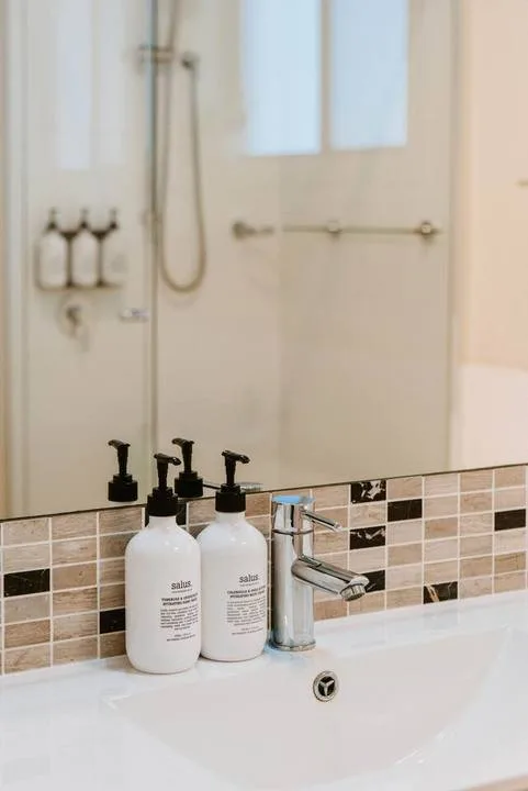 Lavabo de baño con dos dispensadores de jabón y un grifo.