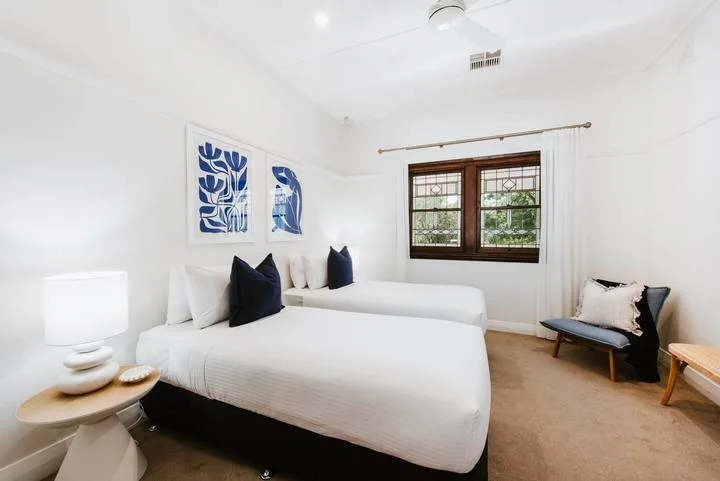 Un dormitorio luminoso con ropa de cama blanca y detalles azules.