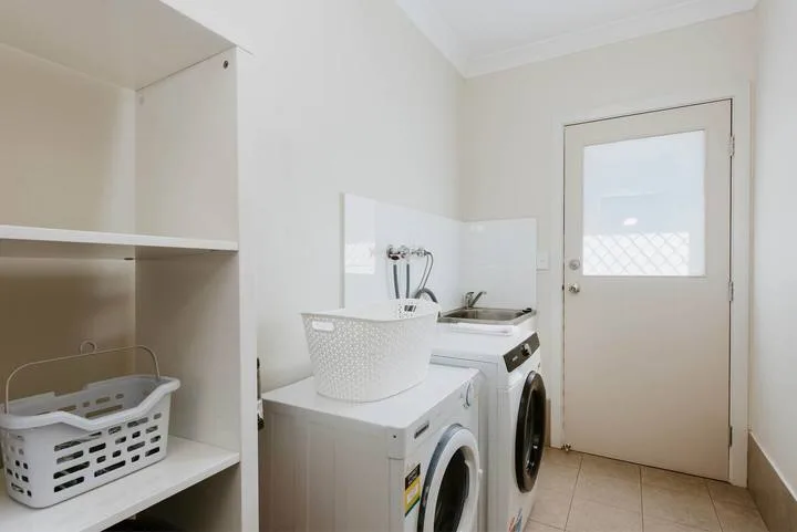 Cuarto de lavandería con lavadora, secadora y estanterías abiertas.