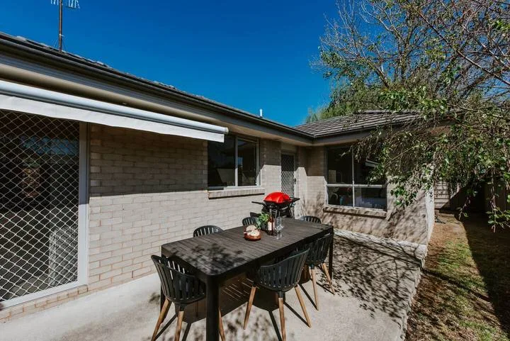 Un patio exterior con una mesa de comedor y sillas junto a la casa.