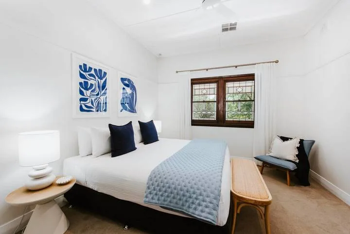 Un dormitorio luminoso con una cama tendida y una ventana.