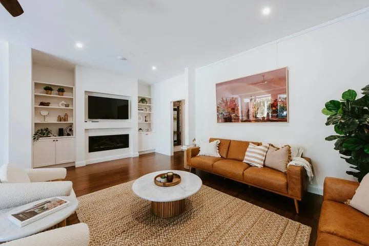 Una sala luminosa con un sofá marrón, una mesa de centro y estanterías empotradas.