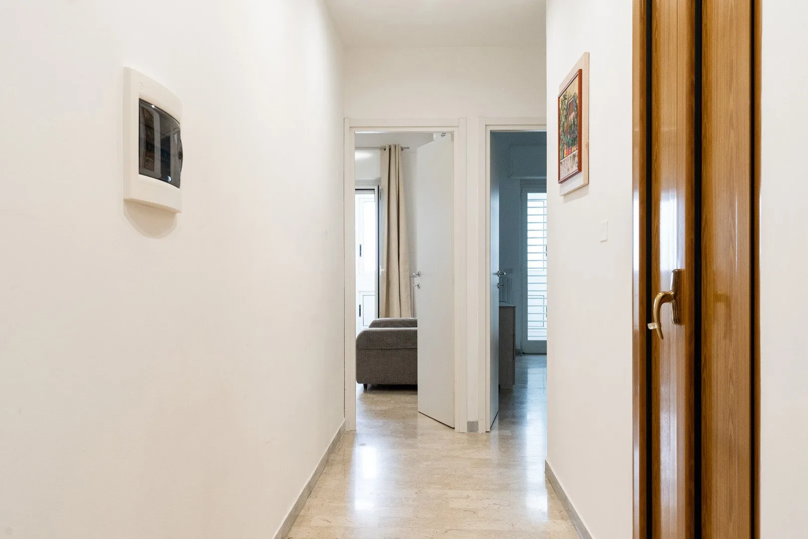 A bright hallway with a polished floor and open doorways.