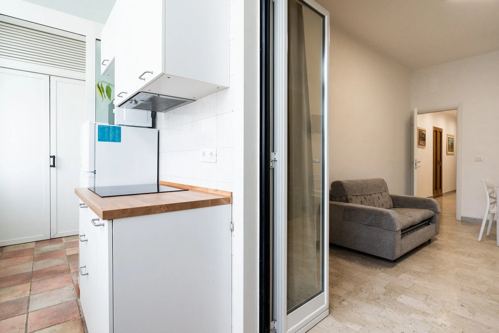 A kitchenette opens onto a living area with a sofa and dining table.