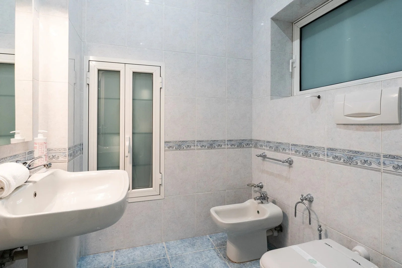 A tiled bathroom with a sink, bidet, and bathtub.
