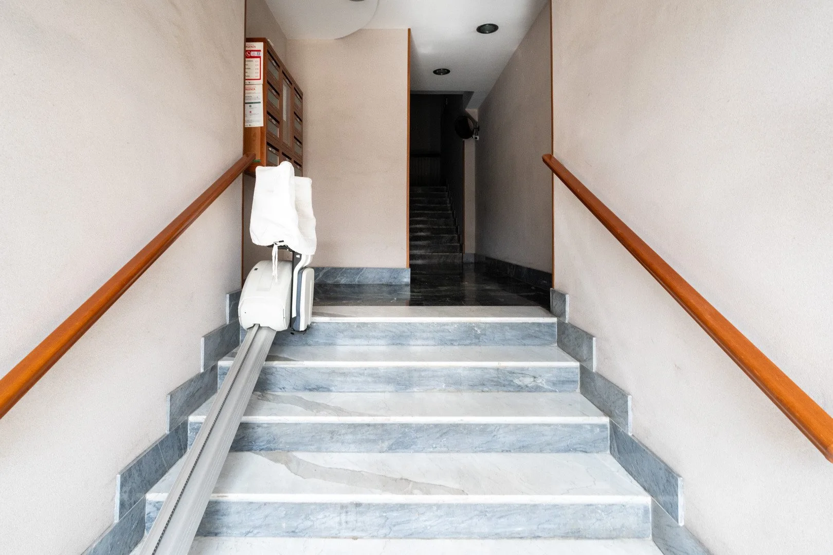 A stairwell with a central staircase and wooden handrails along both walls.