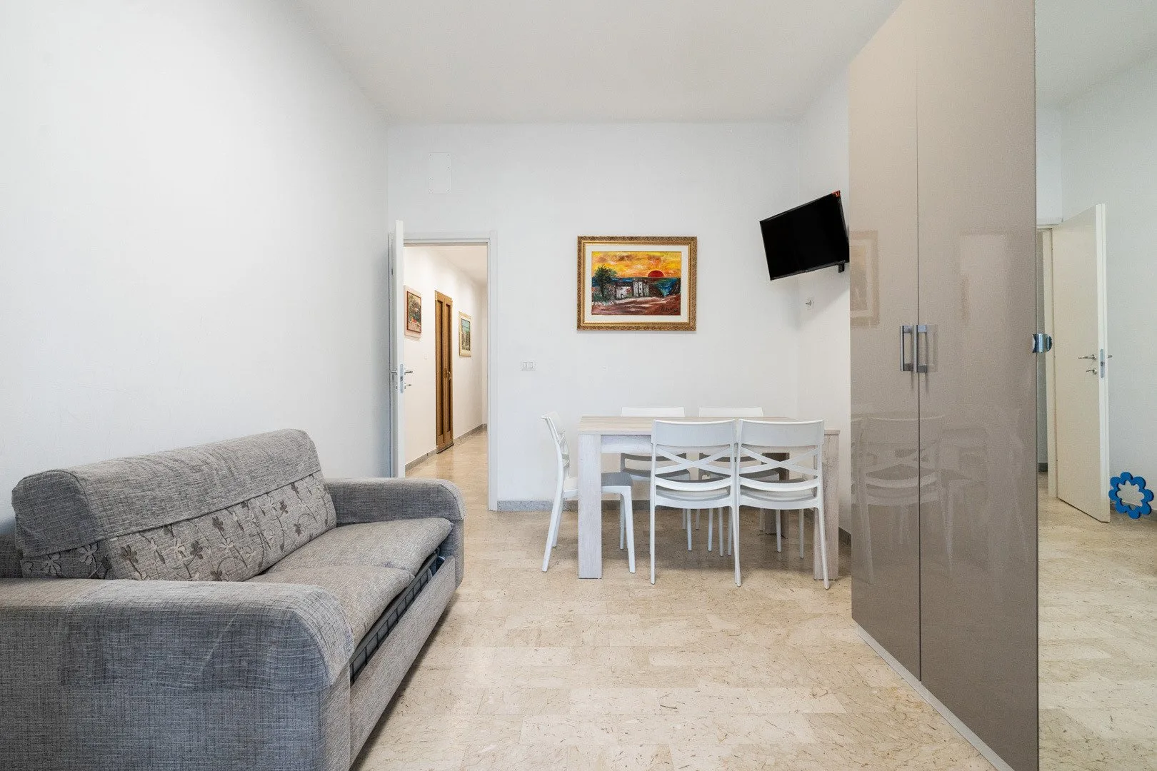 A bright dining and living area with a table, chairs, and gray seating.