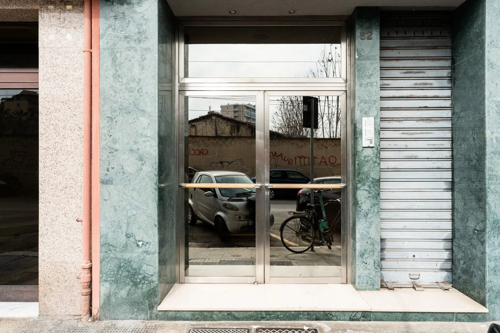 A storefront entrance with glass doors and a closed metal shutter.