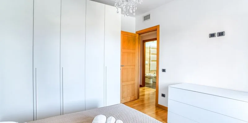 A bright bedroom with built-in wardrobes and an open wooden doorway.