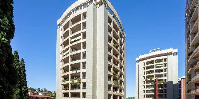 Apartment buildings rise against a clear blue sky.