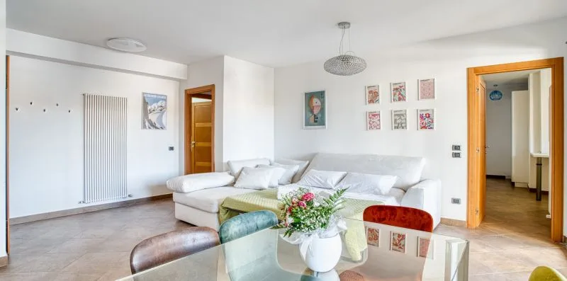 A bright living room with white seating and a glass coffee table.