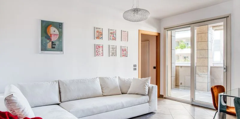 A bright living room with a white sectional sofa and sliding glass doors.