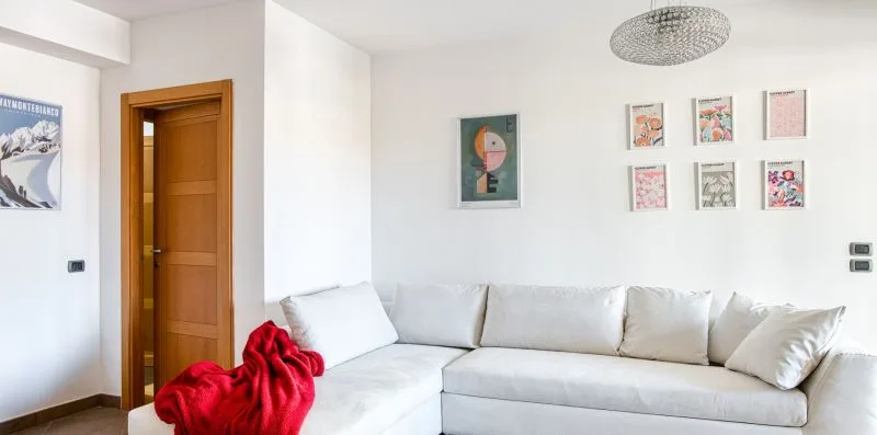 A bright living room with white seating and framed artwork on the walls.