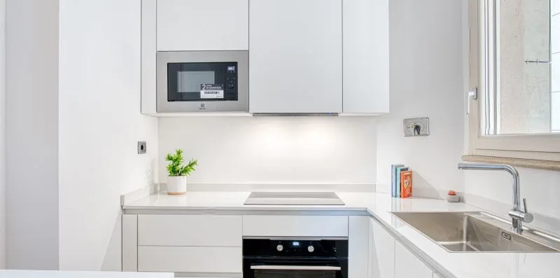 A bright white kitchen with a built-in oven and countertop.