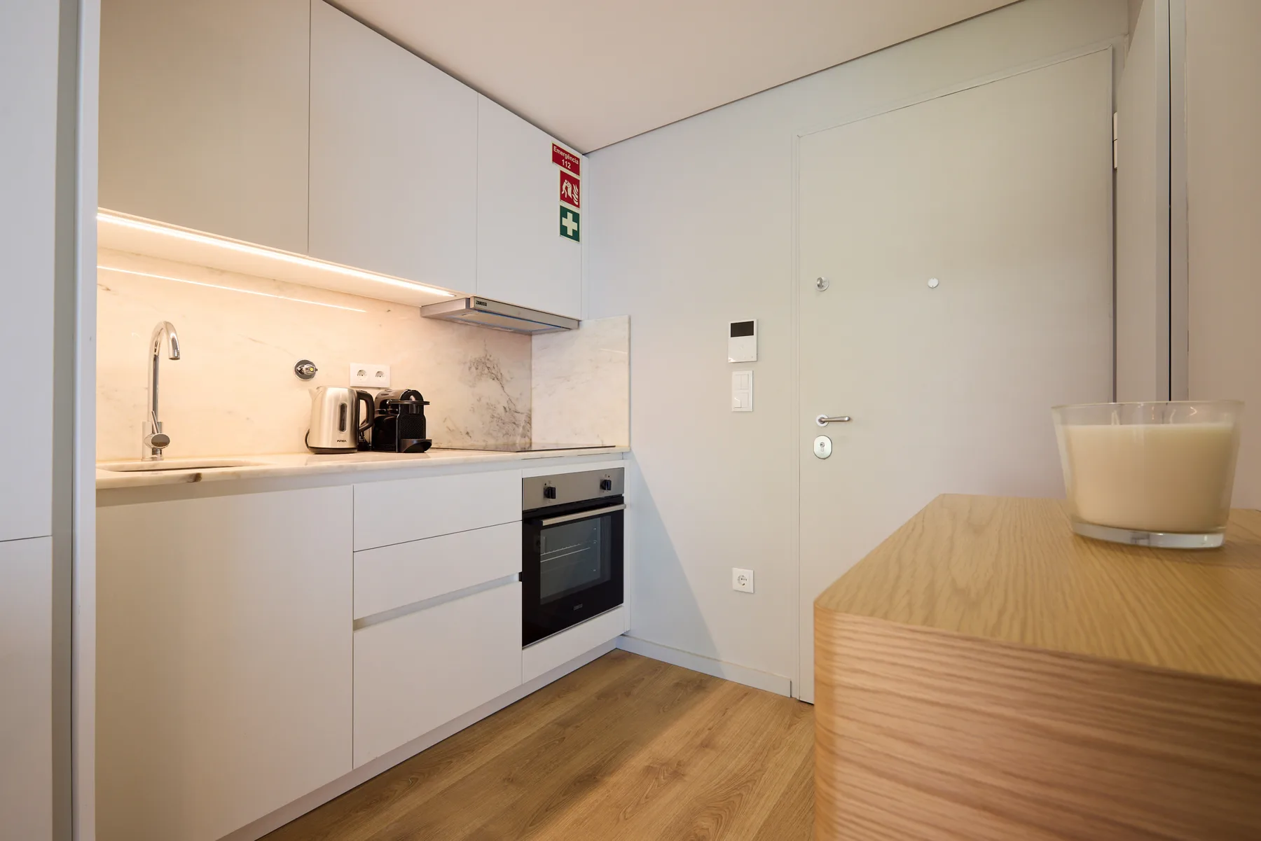 A modern kitchen with white cabinets, a built-in oven, and a wood-finished counter.