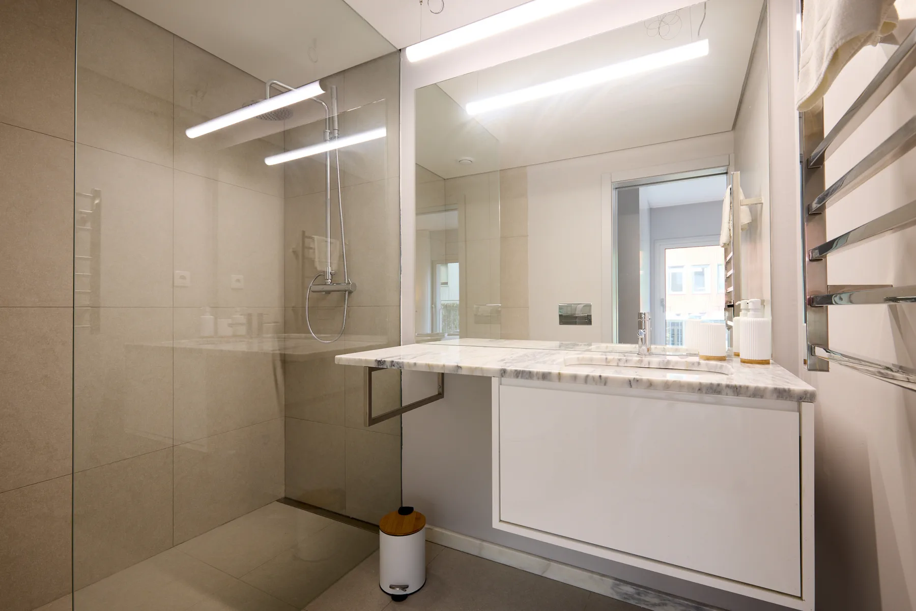Un baño alicatado con una ducha de vidrio y un amplio lavabo.
