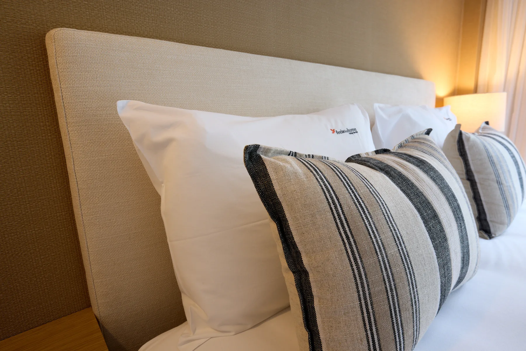 Un dormitorio con una cama bien arreglada y cojines decorativos a rayas.