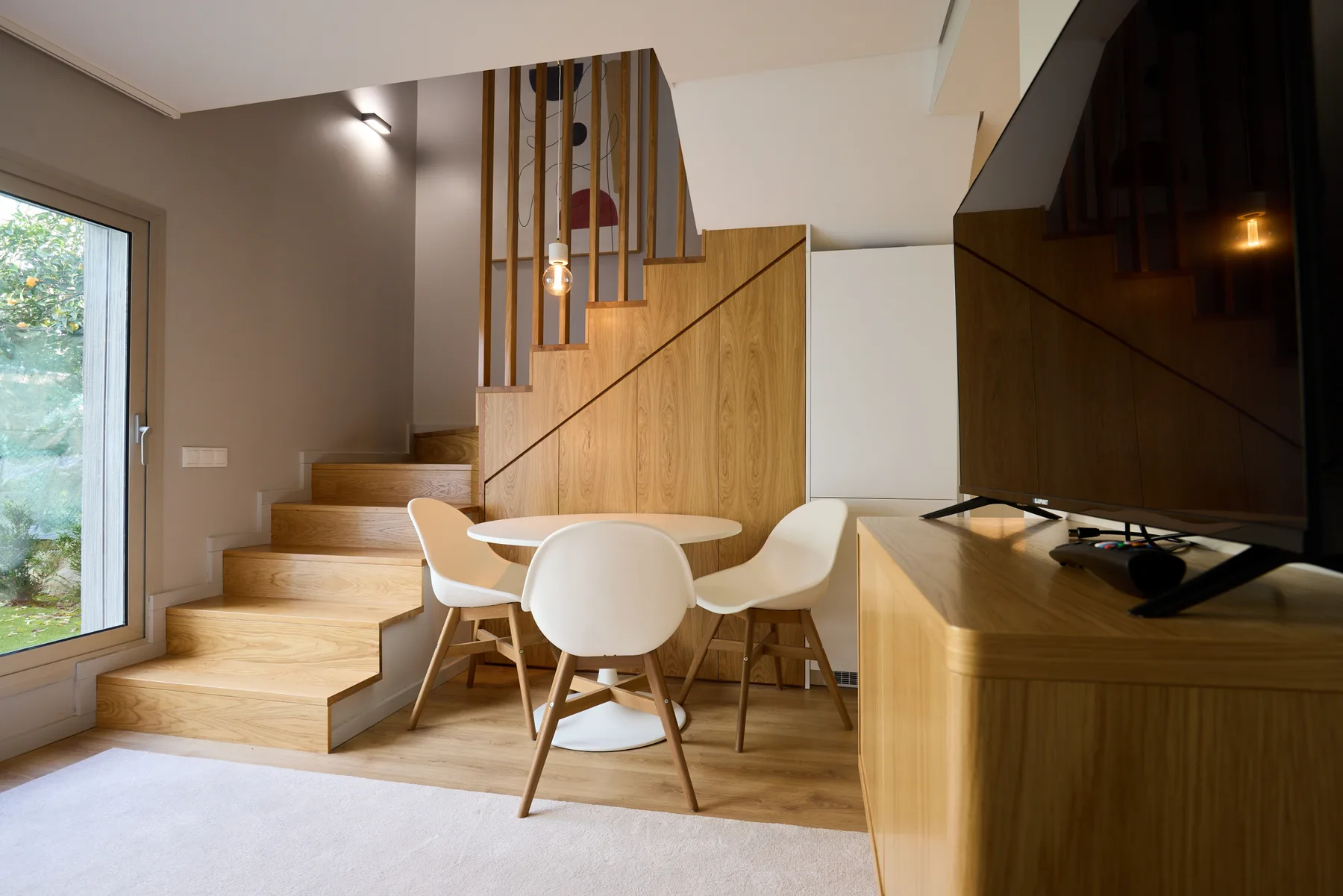 Una sala moderna con una mesa de comedor junto a una escalera de madera.