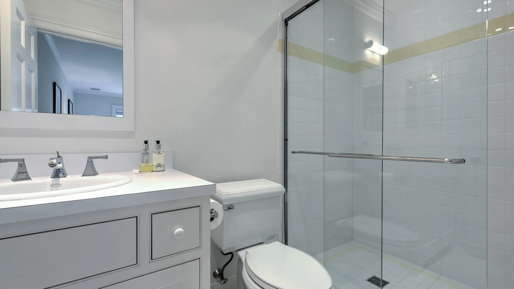 Un baño luminoso con lavabo, inodoro y ducha de vidrio.