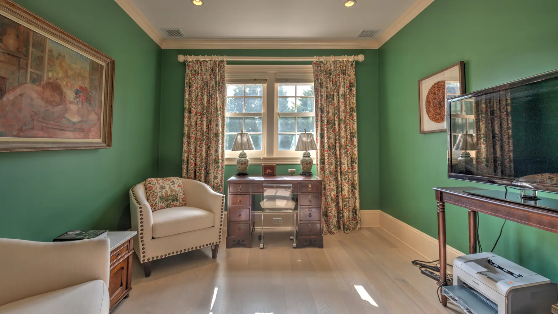 Una sala de estar con paredes verdes, un sillón, un escritorio y una ventana grande.