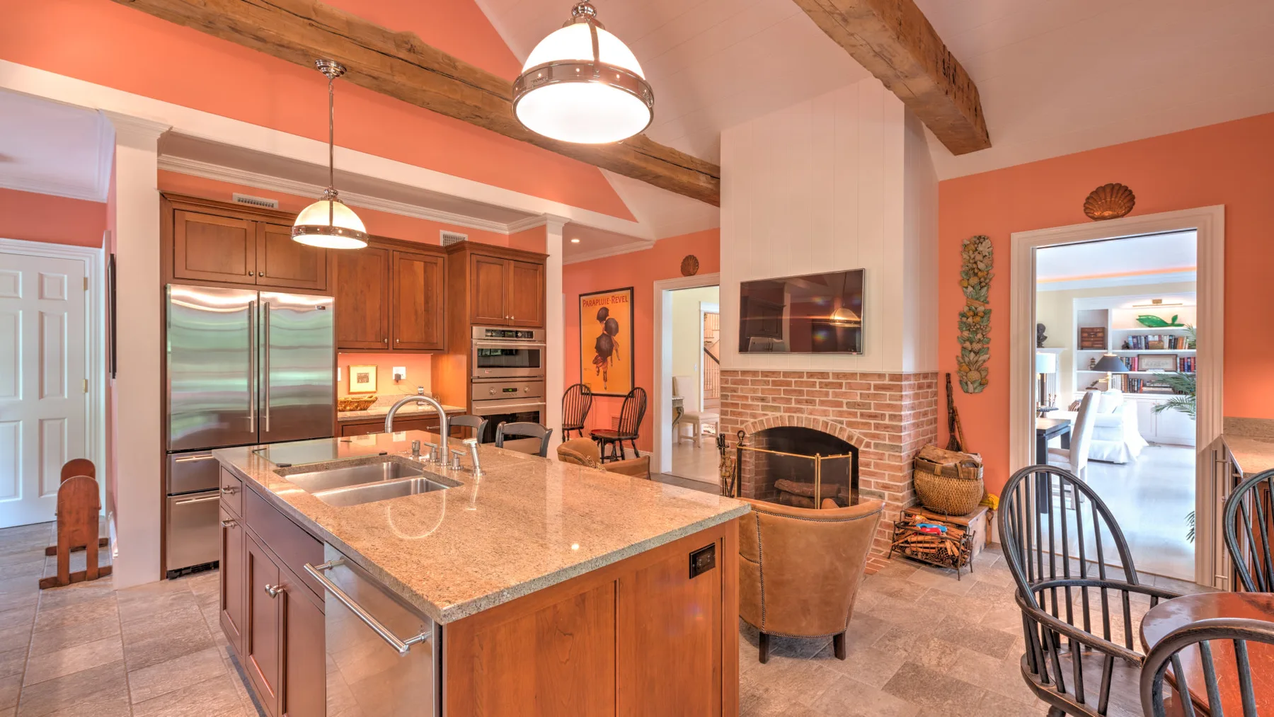 Una cocina abierta al salón, con una isla amplia y una chimenea de ladrillo.